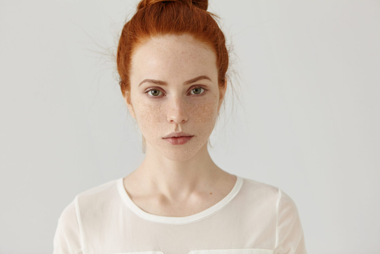 pretty student girl with ginger hair in knot relaxing at home after college headshot of tender charming young woman with freckles wearing white blouse posing