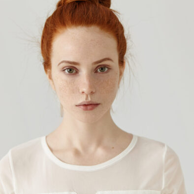 pretty student girl with ginger hair in knot relaxing at home after college headshot of tender charming young woman with freckles wearing white blouse posing